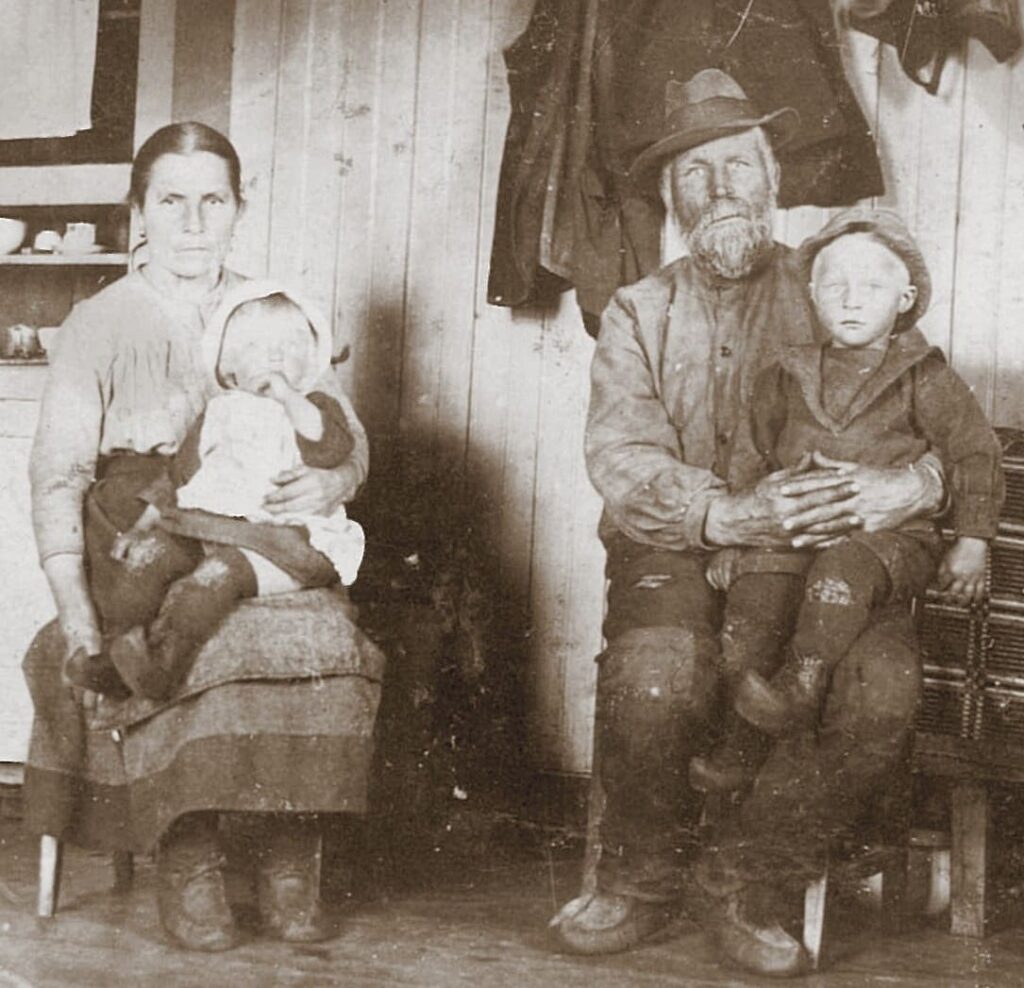 Fattig kvinna och man sitter p&aring; stolar med varsitt barn i kn&auml;t